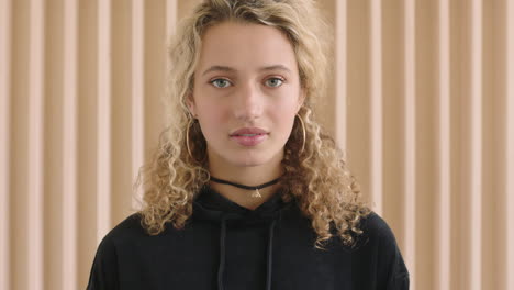 close up portrait of cute young blonde woman looking pensive shy at camera vulnerable femining female wearing black hoodie