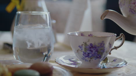 teapot is poured into the teacup in beautiful window lit dining room