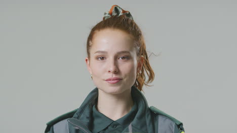 studio portrait of serious young female paramedic against plain background