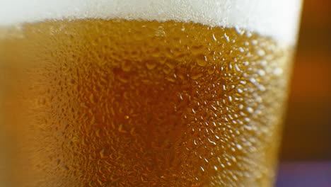 macro shot of a beer glass with cold beer bubbles rise in the glass. slow motion beer bubbles