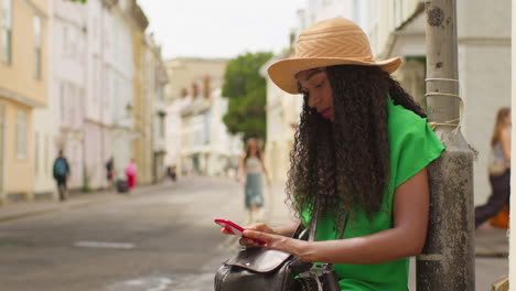 female tourist on vacation in oxford uk exploring city walking along holywell street using mobile phone for directions and information