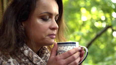 close up fhd shot of a brunette middle-aged woman enjoying the smell of a fresh hot breakfast tea, holding the cup with both hands