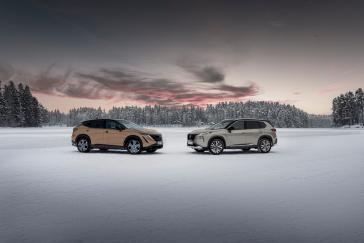 The X-Trail e-POWER e-4ORCE and Ariya e-4ORCE parked on the snow and facing each other with a forest in the background