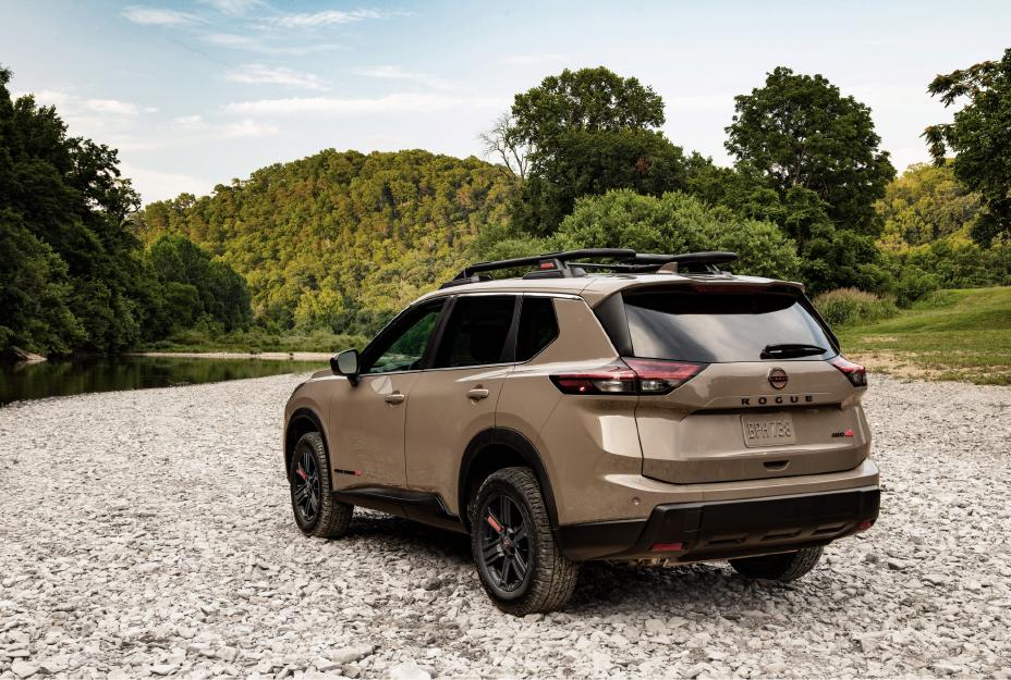 Left rear 3/4 view of the 2025 Nissan rogue parked on rocks with a creek and woods far behind.