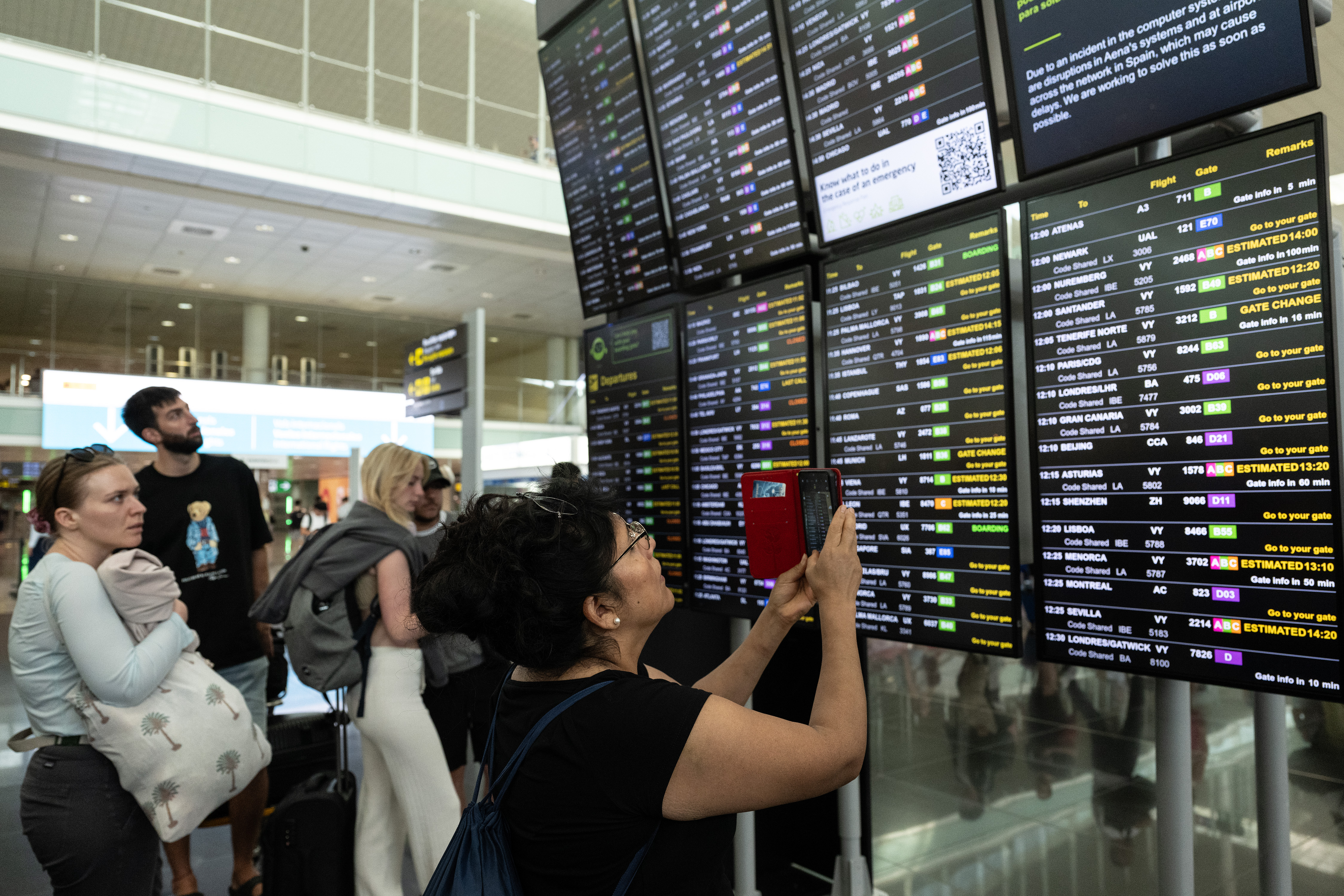 BARCELONA, SPAIN - JULY 19: A passenger takes pictures of a screen displaying delayed flights at Barcelona Aiport on July 19, 2024 in Barcelona, Spain. Businesses, travel companies and Microsoft users across the globe were among those affected by a tech outage today. (Photo by David Ramos/Getty Images)