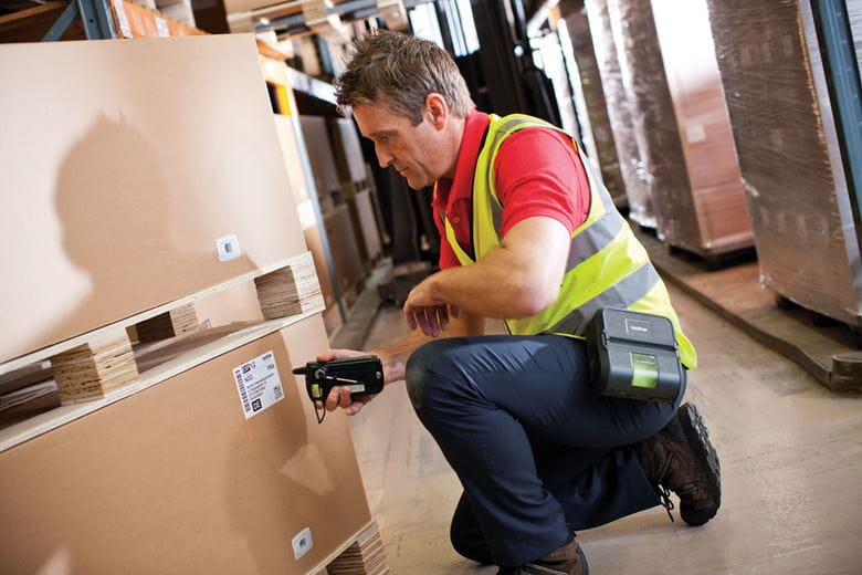 Warehouse worker scanning box label with RJ printer on belt clip