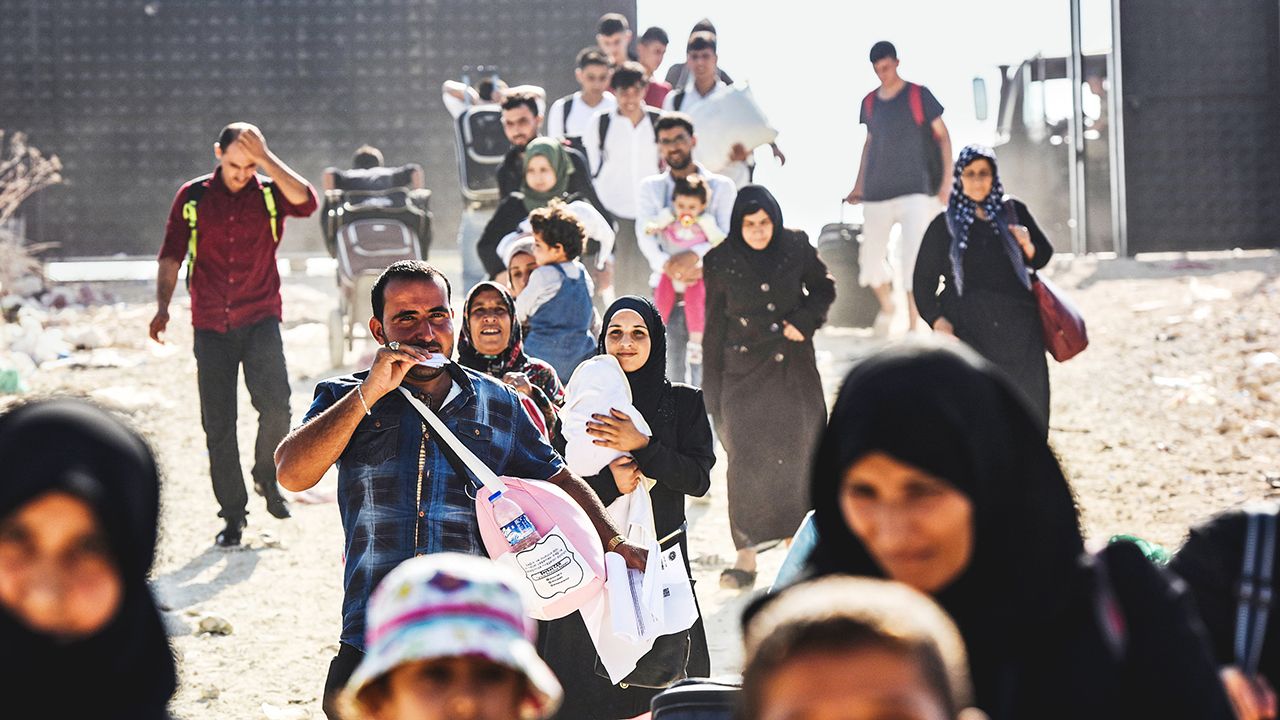 TOPSHOT - Syrian refugees arrive at the Oncupinar crossing gate, close to the town of Kilis, south central Turkey, in order to cross to Syria for the Eid al-Adha Muslim holiday, on August 28, 2017.Turkish authorities allow Syrian refugees to visit their country for Eid-Al-Adha (Feast of the Sacrifice) celebrities. / AFP PHOTO / BULENT KILIC        (Photo credit should read BULENT KILIC/AFP via Getty Images)