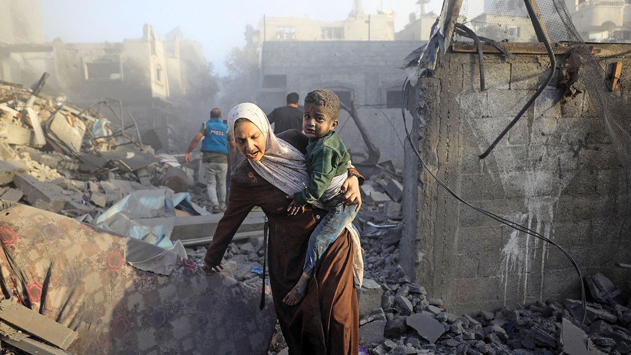 A woman flees with her child following Israeli air strikes in the al-Maghazi refugee camp in the Gaza Strip