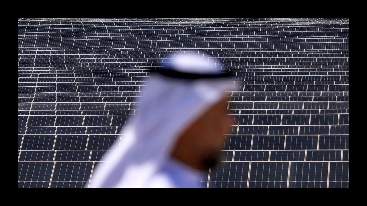 An Emirati man stands in front of photovoltaic panels at al-Dhafra project in UAE