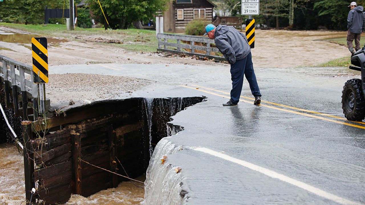 A passerby inspects the collapsed portion of a bridge after flood waters destroyed it during Tropical Storm Helene, in Boone, North Carolina.