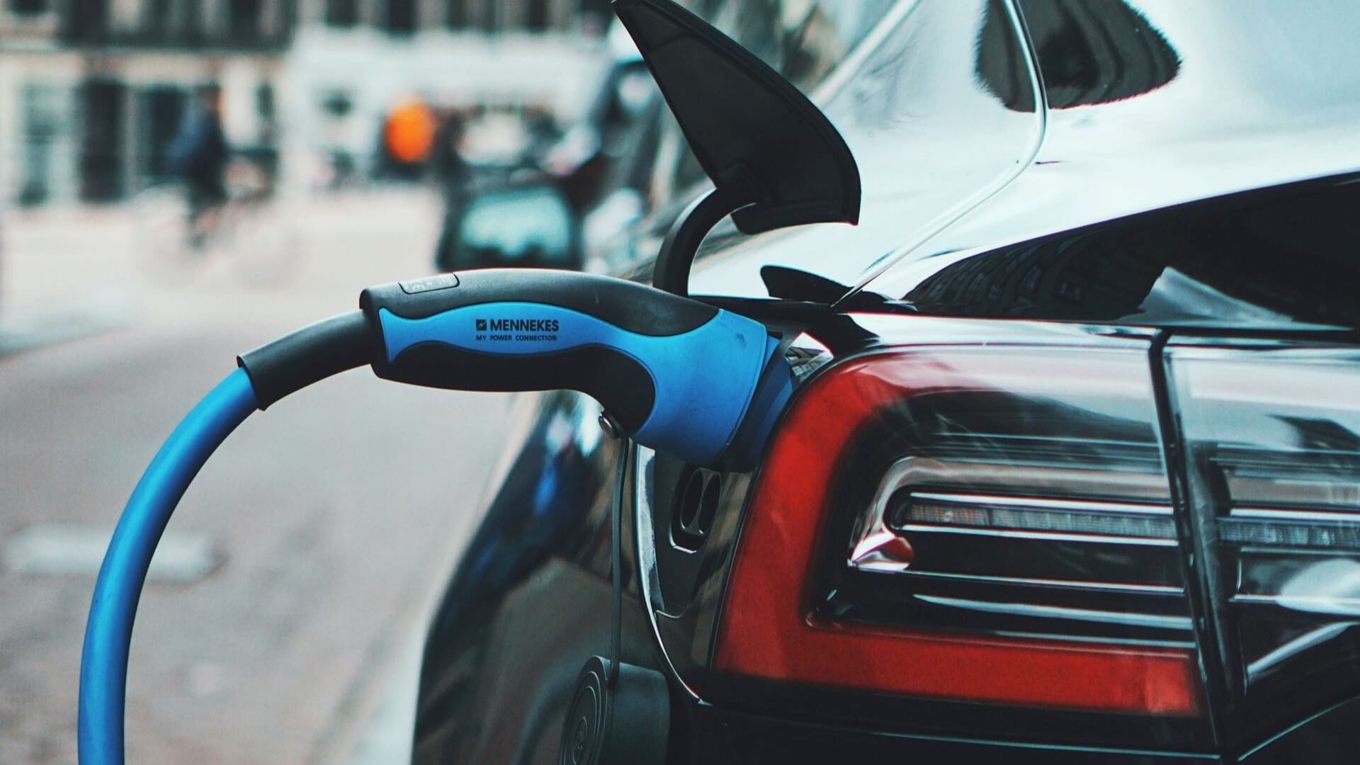 Close up of electric fuelling cable connected to rear charging port of black car