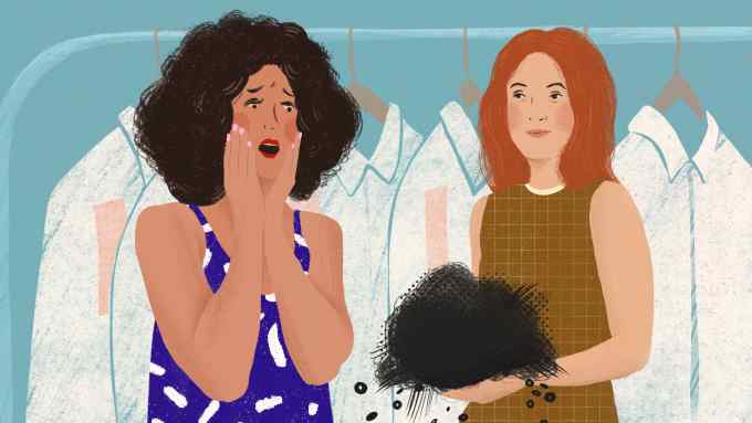 An illustration of two women, one with dark curly hair in a blue dress looking horrified, and the other with red hair in a brown dress holding a bundle of black fabric. They are standing in front of a row of white shirts hanging on a rack