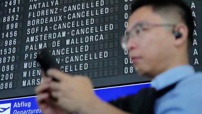 A mans stands in front ot the dpartures board displaying cancelled flights at Frankfurt airport