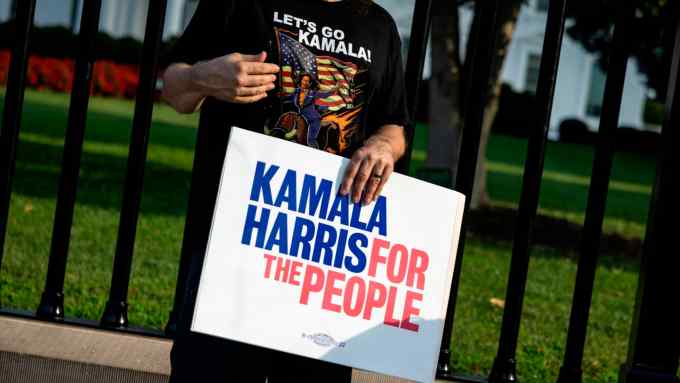 A man wearing a ‘Let’s Go Kamala’ T-shirt holds a sign that says ‘Kamala Harris For the People’ in front of the White House on Sunday