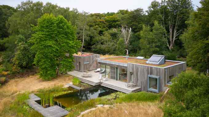 silvery wood house and pool with decking surrounded by woods