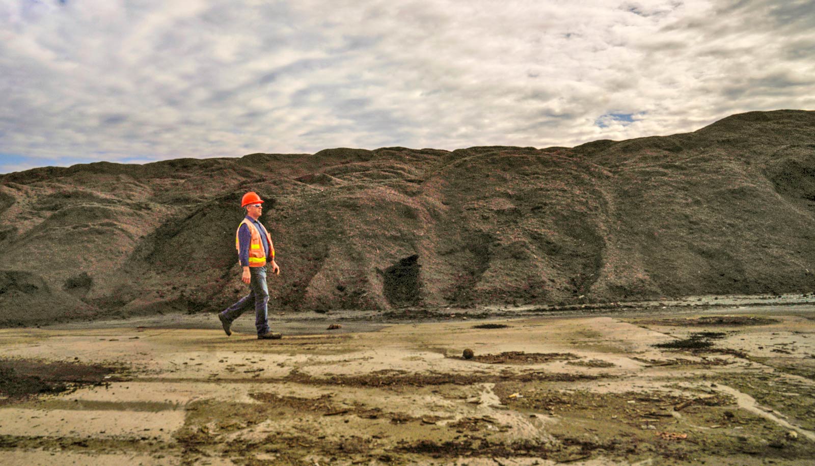 person in high-vis gear walks past brown hills