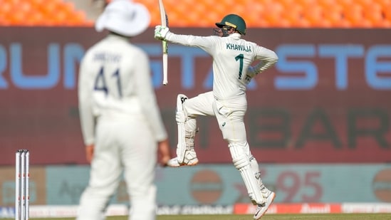 Australia's Usman Khawaja, right, jumps into the air while celebrating his century (AP)