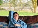 Kareena Kapoor relaxes on a couch with zebras grazing behind her.