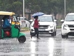 A woman with an umbrella crossing a busy road as rain lashed Chandigarh.  (Ravi Kumar/ HT)