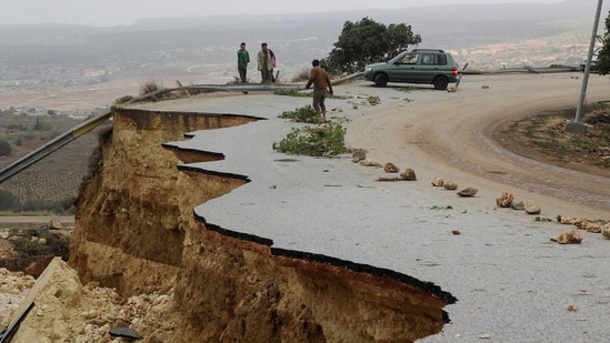 People stand on a damaged road as a powerful storm and heavy rainfall hit Shahhat City, Libya, on September 11.(Omar Jarhman / Reuters)