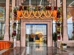 An entrance to the newly constructed airport in Ayodhya is decorated with flowers ahead of its inauguration on Saturday. The airport, positioned approximately 15 km from Ayodhya's main city, incorporates modern construction materials in its core. However, the terminal's exterior, akin to the design of the new Ayodhya station building, embraces a traditional aesthetic. Even the primary gateway follows a similar construction approach, featuring a concrete core adorned with sandstone cladding that showcases stylized carvings.(ANI)