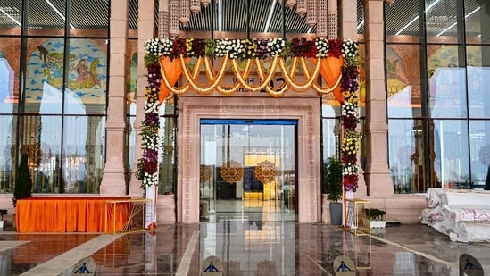 An entrance to the newly constructed airport in Ayodhya is decorated with flowers ahead of its inauguration on Saturday. The airport, positioned approximately 15 km from Ayodhya's main city, incorporates modern construction materials in its core. However, the terminal's exterior, akin to the design of the new Ayodhya station building, embraces a traditional aesthetic. Even the primary gateway follows a similar construction approach, featuring a concrete core adorned with sandstone cladding that showcases stylized carvings.(ANI)