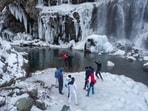 Tourists visit a partially frozen waterfall in Drang village, northwest of Srinagar. Kashmir has been going through a prolonged dry spell and a 79 per cent deficit in rainfall was recorded for December.(AP)