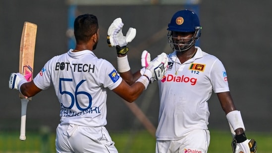 Dinesh Chandimal celebrates after scoring a century (100 runs) with Angelo Mathews (R) during Day 2 of the one-off Test cricket match between Sri Lanka and Afghanistan.(AFP)