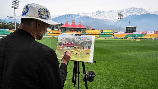 Andy Brown, a British artist, paints the cricket field during a practice session at the Himachal Pradesh Cricket Association Stadium in Dharamsala (AFP)