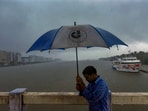 A man uses an umbrella in the rain on Wednesday, May 29, 2024, against the backdrop of Kochi's backwaters.(PTI)