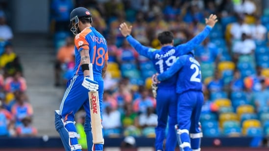 India's Virat Kohli (L) walks off the field after being dismissed by Afghanistan's captain Rashid Khan (R).(AFP)