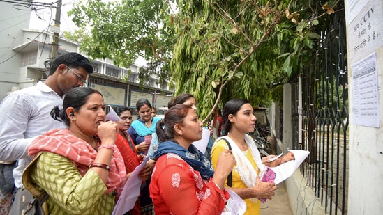 Aspirants search their roll numbers for seats before entering an examination center to appear in the UGC-NET exam.(PTI)