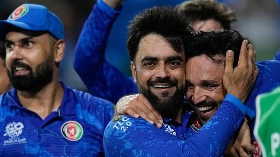 Afghanistan's captain Rashid Khan, centre, embraces teammate Gulbadin Naib as they celebrate after defeating Bangladesh by eight runs in their men's T20 World Cup cricket match at Arnos Vale Ground, Kingstown, Saint Vincent(AP)