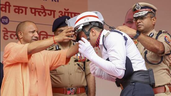 Uttar Pradesh chief minister Yogi Adityanath distributing air-conditioned helmet to traffic police personnel in Lucknow on Thursday. (ANI PHOTO)