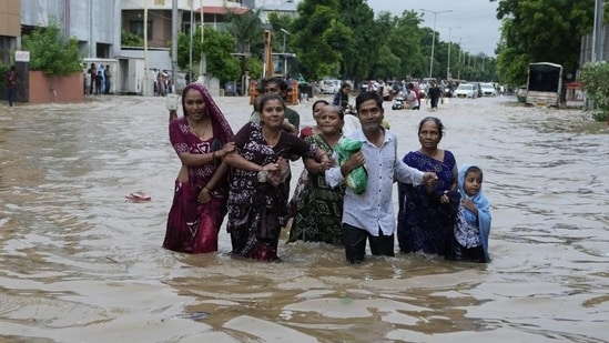 A family wades through a waterlogged road after heavy rainfall in Ahmedabad, Gujarat, on Wednesday. Intense monsoon rains and flooding have hit Gujarat, killing at least 28 people in the last three days, according to government officials.(AP)