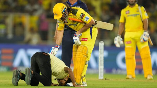 A fan comes on to the playing field and prostrates in front of Chennai Super Kings' MS Dhoni during the Indian Premier League cricket match between Chennai Super Kings and Gujarat Titans in Ahmedabad, India, Friday, May 10, 2024. (AP Photo)