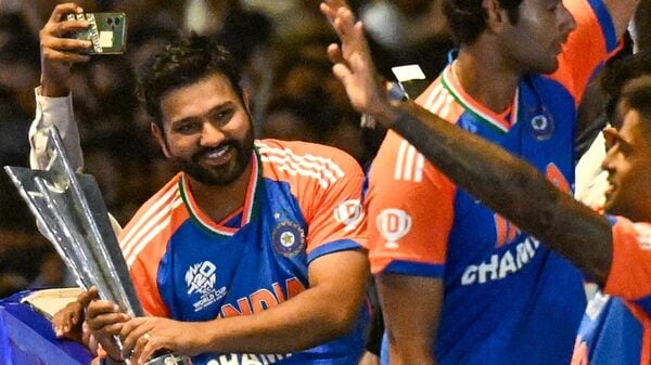 Indian cricket captain Rohit Sharma (L) holds the trophy as he greets fans during an open bus roadshow upon arrival in Mumbai on July 4, 2024, after winning the ICC men's Twenty20 World Cup in Barbados. (Photo by Punit PARANJPE / AFP)