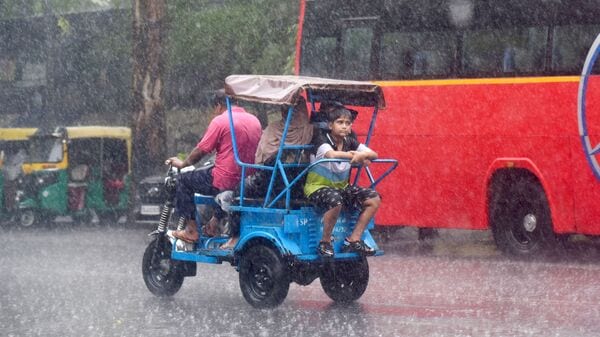 New Delhi, June 29 (ANI): An e-rickshaw with passengers ride past during a monsoon rainfall, in New Delhi on Saturday. (ANI Photo/Ritik Jain) 