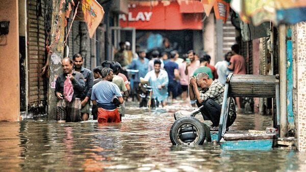 People wade through a waterlogged road near Sarai Kale Khan area in New Delhi after heavy rain on 28 June  (PTI)