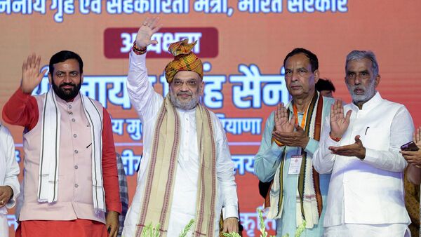 Union Home Minister Amit Shah waves to the gathering with Haryana Chief Minister Nayab Singh Saini during the 'Backward Class Samman Sammelan' organised at Central University of Haryana, in Mahendragarh on Tuesday