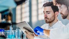 Two workers in a laboratory looking at a tablet 