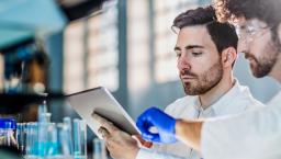 Two workers in a laboratory looking at a tablet 