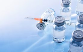 Vials with medication and syringe on a blue table