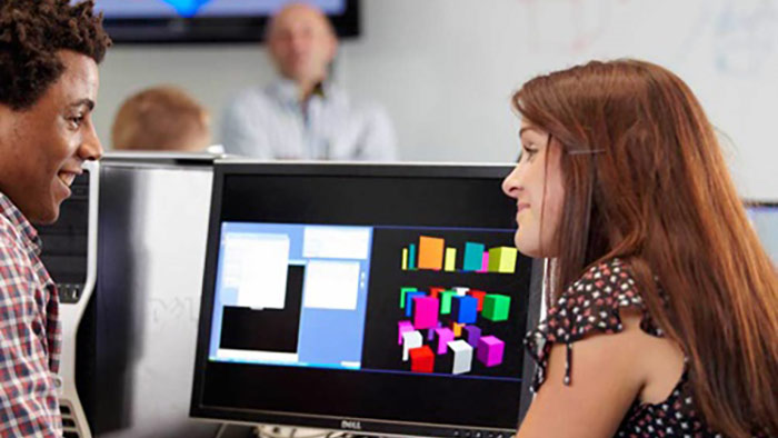 Two students sat in front of a pc monitor in discussion