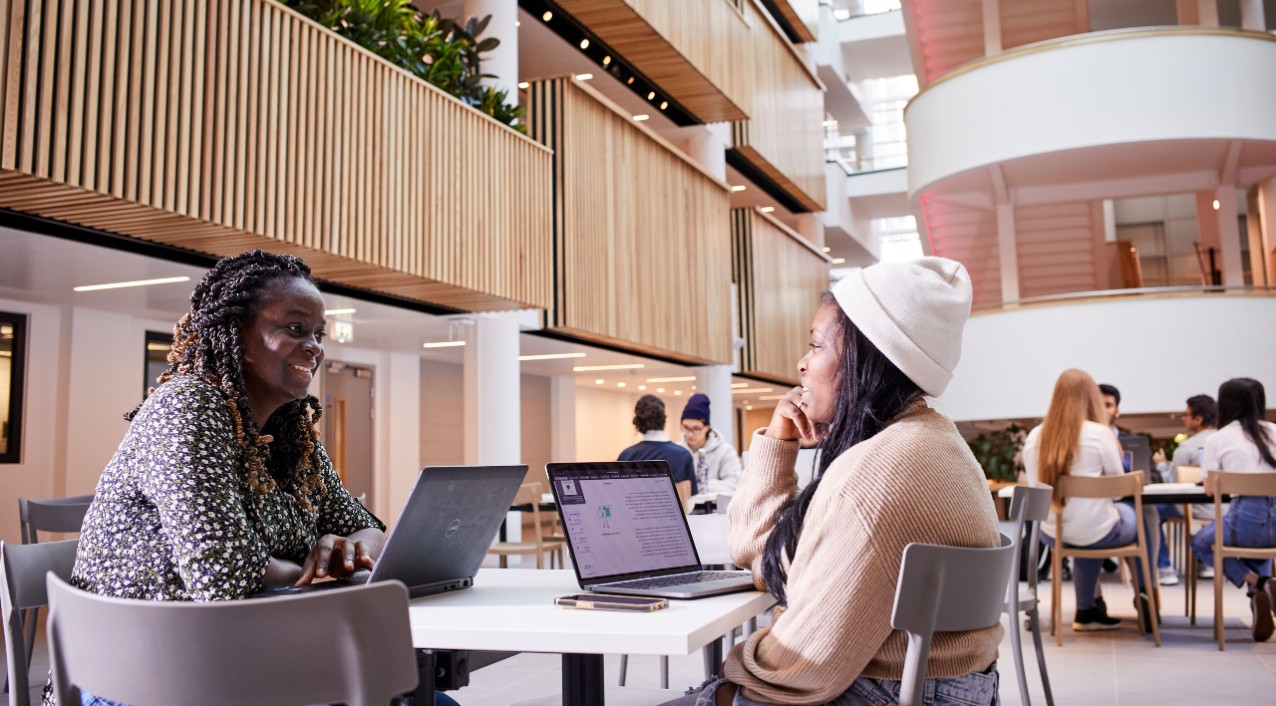 Two students sat at a table talking in the Sheffield Hallam atrium