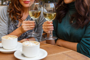 Woman drinking wine and coffee in a cafe