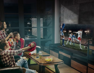 Four people watching soccer on wall-mounted TV with a soundbar underneath in a living room