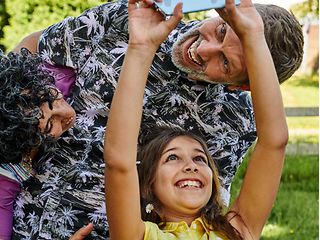 A snapshot of a laughing family just taking a selfie with a smartphone.