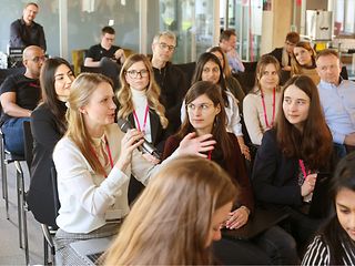 Sitting in a group of Femtec participants, one speaks into a microphone