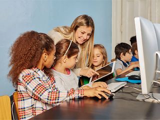 Teacher shows children something on a tablet